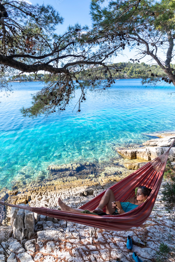 woman with smartphone in hammock on island mljet, croatia