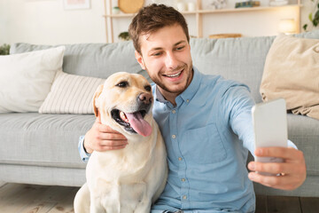 Young man with his dog taking selfportrait at home