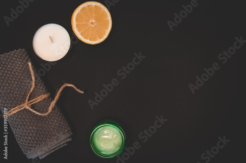 Elements for relaxing and spa. Lemon, cream, grey terry towel, the candle on the black background.