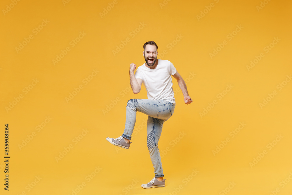 Happy young bearded man guy in white casual t-shirt posing isolated on yellow background studio portrait. People sincere emotions lifestyle concept. Mock up copy space. Clenching fists like winner. Happy young bearded man guy in white casual t-shirt posing isolated on yellow background studio portrait. People sincere emotions lifestyle concept. Mock up copy space. Clenching fists like winner.