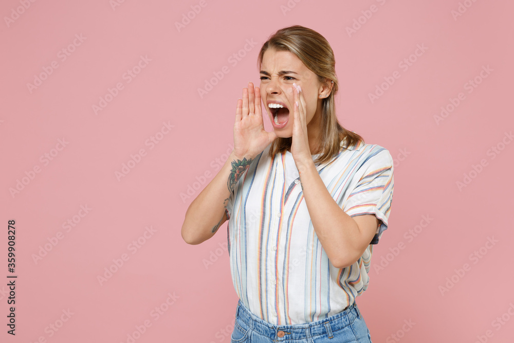 Irritated young blonde woman girl in casual striped shirt posing isolated on pastel pink background studio portrait. People lifestyle concept. Mock up copy space. Scream with hands gesture near mouth. Irritated young blonde woman girl in casual striped shirt posing isolated on pastel pink background studio portrait. People lifestyle concept. Mock up copy space. Scream with hands gesture near mouth.