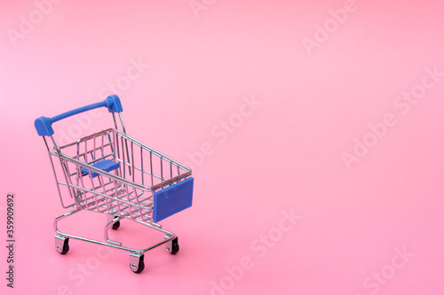 Shopping concept : Blue shopping cart on pink background. online shopping consumers can shop from home and delivery service. with copy space.