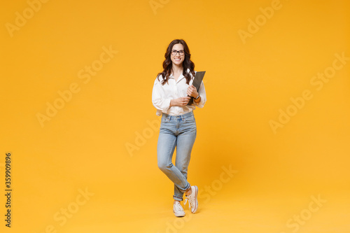 Smiling young brunette business woman in white shirt glasses isolated on yellow background studio. Achievement career wealth business concept. Mock up copy space. Hold clipboard with papers document.