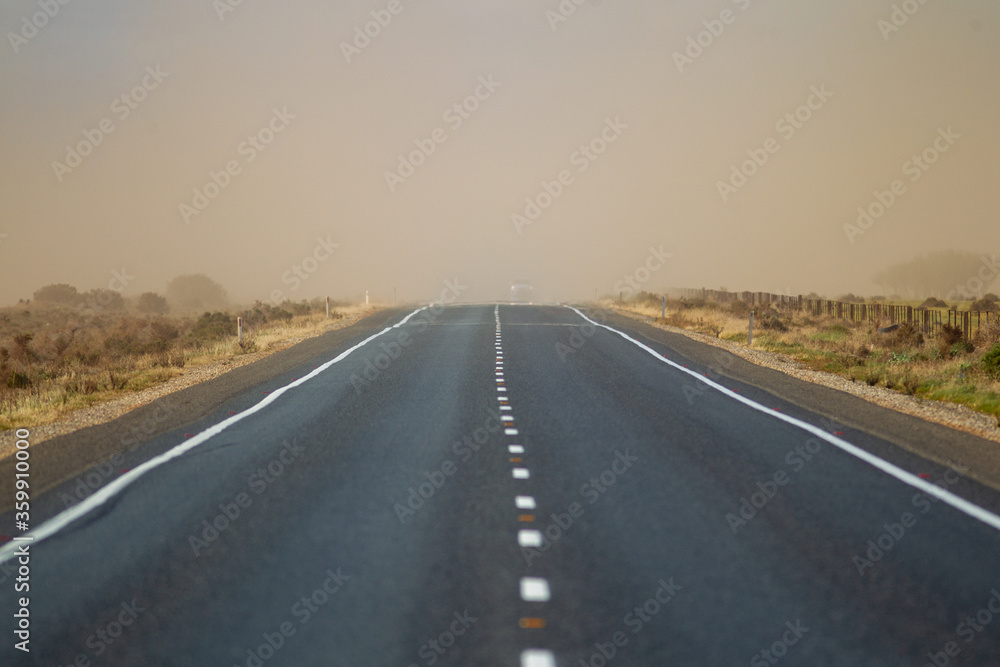 A stretch of highway road with a passing dust storm in country south australia on 20th June 2020