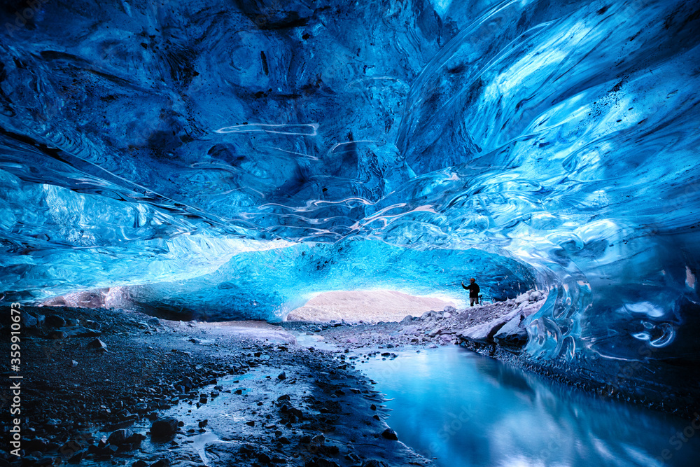 Man takes a photo in the opening of an ice cave in the Vatnajokull glacier in southeast Iceland