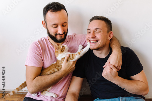 Gay couple playing with kitten. photo