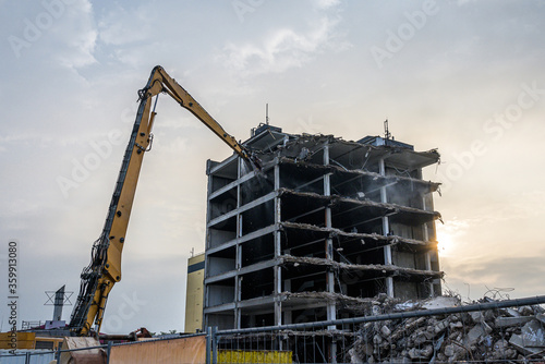 Building House Demolition site Excavator with hydraulic crasher machine and yellow container photo