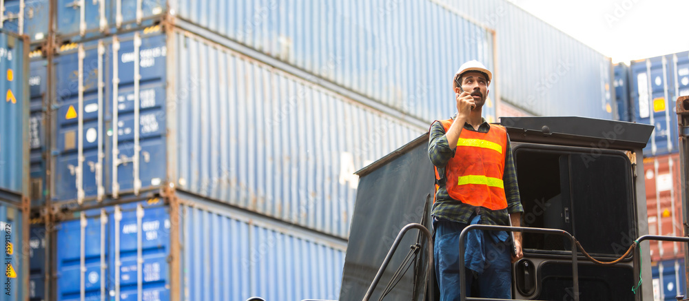 foreman maneger working through a radio communication with the workers in the container yard at port of import and export goods. foreman maneger working through a radio communication with the workers in the container yard at port of import and export goods.