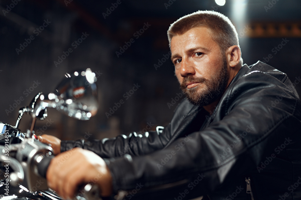 Man motorcyclist sitting on his motorbike in underground parking Man motorcyclist sitting on his motorbike in underground parking