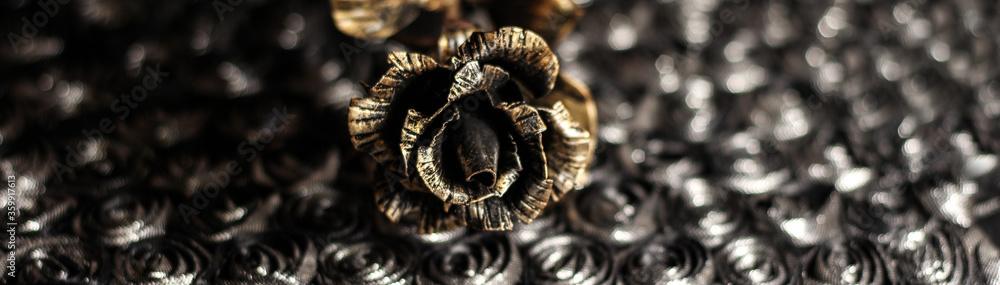 An iron rose on a shiny dark background. Bronze flower. An iron rose on a shiny dark background. Bronze flower.