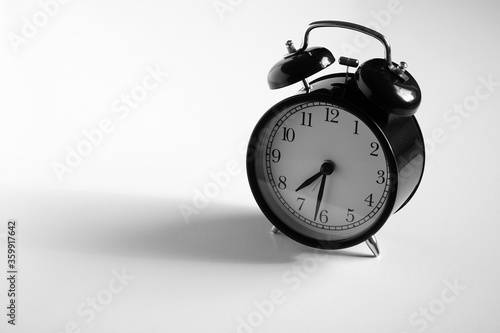 Black vintage alarm clock on table. White background. Wake up concept. An image of a retro clock showing 07:32 pm/am. 