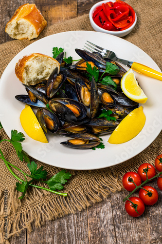 Delicious Seafood Mussels with Lemon and Parsley. Clams in the Shells on Wooden Background. Selective focus.