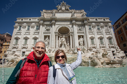 Coppia di turisti anziani lancia una moneta nella fontana di Trevi a Roma photo