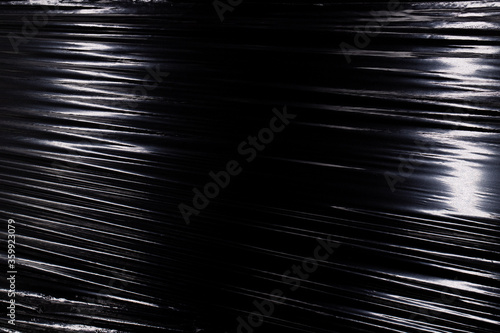 Texture of a stretched plastic film on a black background, food rumpled cellophane wrap photo