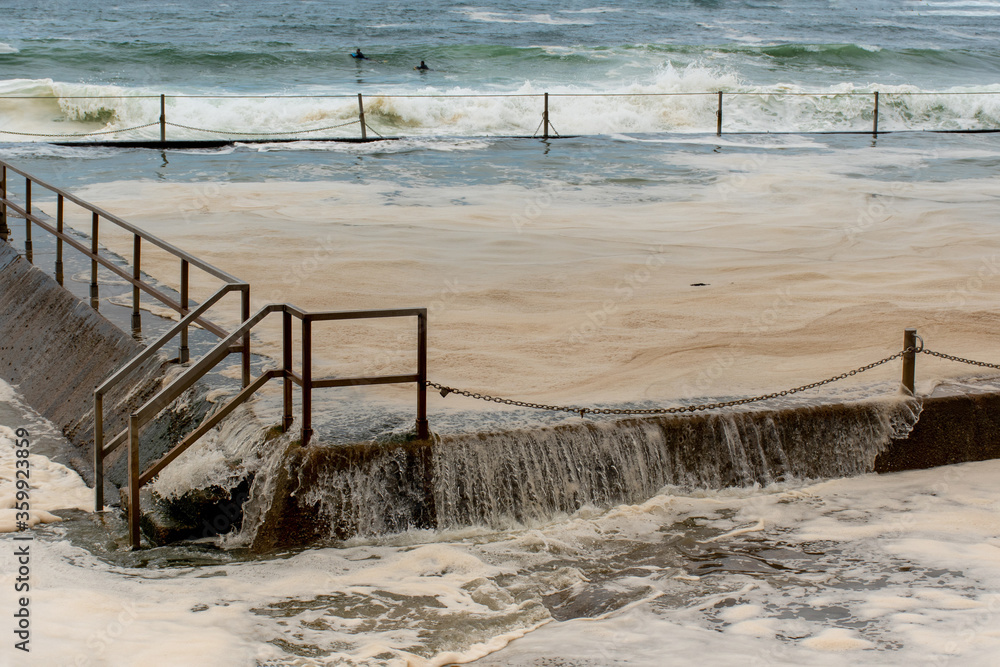 Ocean storm aftermath: A mass of thick foam covered the rock pool following extreme storm weather at Cronulla, NSW, Australia Ocean storm aftermath: A mass of thick foam covered the rock pool following extreme storm weather at Cronulla, NSW, Australia