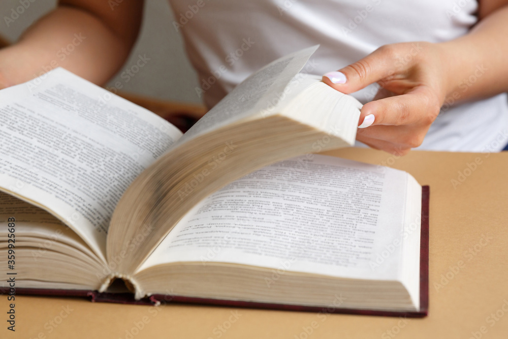 A woman is reading a book. Hands are holding a book. Beautiful manicure. A student is studying a textbook. The concept of education and study of information A woman is reading a book. Hands are holding a book. Beautiful manicure. A student is studying a textbook. The concept of education and study of information