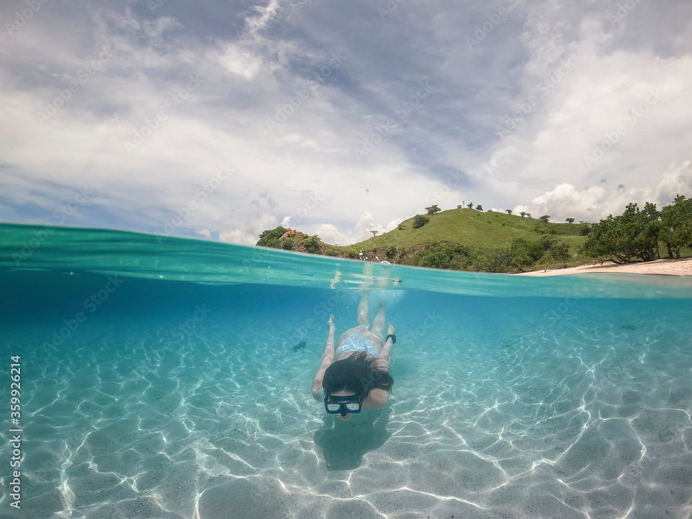 Half water view of woman in white bikini snorkeling. pink sand at Komodo island, Indonesia. Half water view of woman in white bikini snorkeling. pink sand at Komodo island, Indonesia.