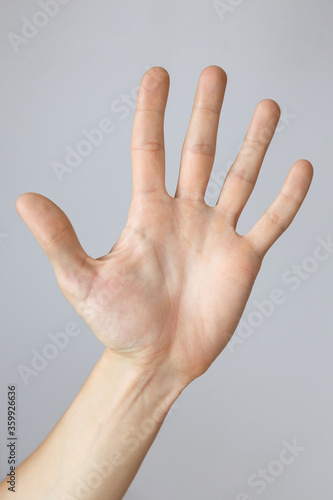 Gesture and sign, male hand showing stop on a light background