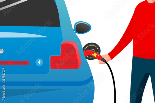Blue electric car at the charging station with a young man holding the cable