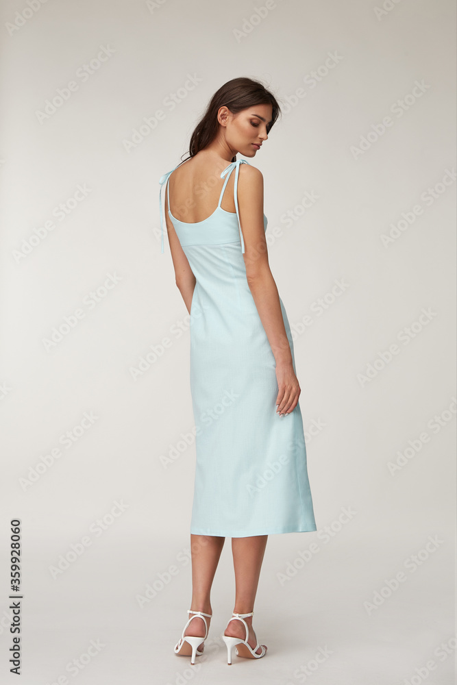 Woman beautiful face natural make up brunette hair tanned skin body wear fashion summer collection organic cotton long light blue skinny dress style for romantic date walk, accessory shoes sandals. Woman beautiful face natural make up brunette hair tanned skin body wear fashion summer collection organic cotton long light blue skinny dress style for romantic date walk, accessory shoes sandals.
