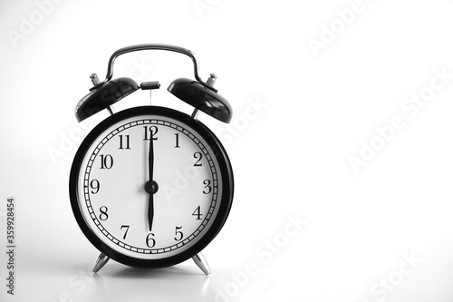 Black vintage alarm clock on table. White background. Wake up concept. An image of a retro clock showing 06:00 pm/am. 