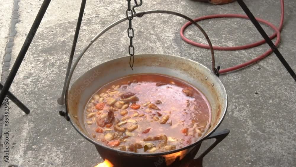 Cooking Delicious Beans In A Huge Pot Over The Stove Outdoor - Revealed Beside The Table - revealing shot Cooking Delicious Beans In A Huge Pot Over The Stove Outdoor - Revealed Beside The Table - revealing shot