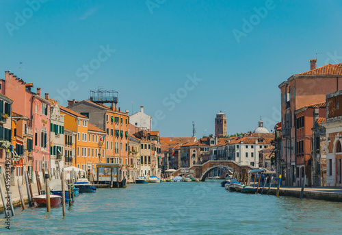 View of a canal in Venice, Italy, with boats, docks, ancient buildings and clear sky