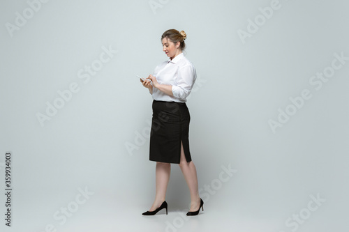 Leader. Young woman in office attire. Bodypositive female character, feminism, loving herself, beauty concept. Plus size businesswoman on gray background. Boss, beautiful. Inclusion, diversity.