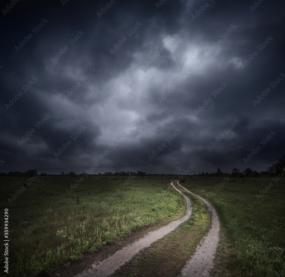 Dramatic stormy sky over field and dirt road