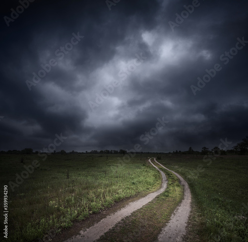 Dramatic stormy sky over field and dirt road