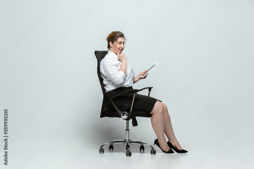 Gadgets. Young woman in office attire. Bodypositive female character, feminism, loving herself, beauty concept. Plus size businesswoman on gray background. Boss, beautiful. Inclusion, diversity. Gadgets. Young woman in office attire. Bodypositive female character, feminism, loving herself, beauty concept. Plus size businesswoman on gray background. Boss, beautiful. Inclusion, diversity.
