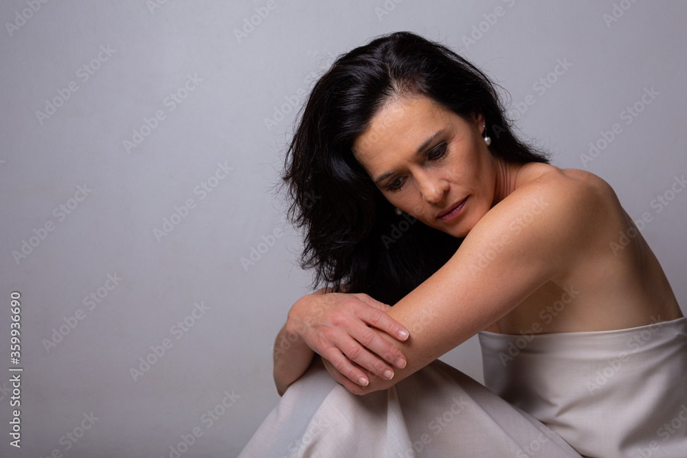 Conceptual image of a woman sad and lone on a bed under a sheet Conceptual image of a woman sad and lone on a bed under a sheet