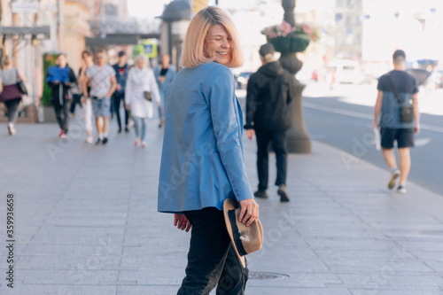 Portrait of a young stylish woman walking along the street, dressed in a casual outfit