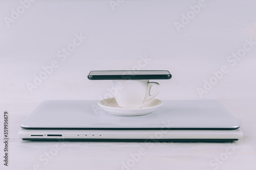 Laptop with coffee and smartphone on a white, wooden table.