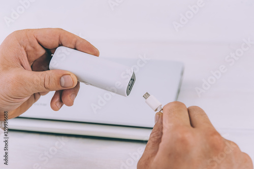 Man charges a portable charger through a laptop.