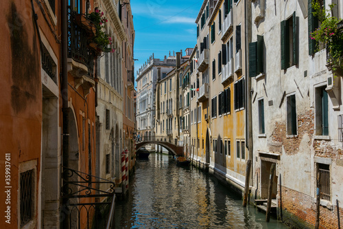 Typical canal in Venice, italy, between ancient buildings with bridge in the distance © Simone