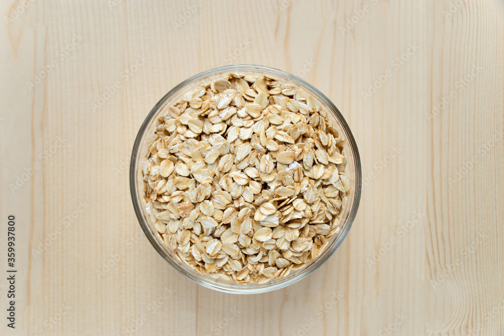 Top view raw oat flakes in bowl on wooden background. Uncooked oatmeals. Healthy food, dieting concept. healthy lifestyle Top view raw oat flakes in bowl on wooden background. Uncooked oatmeals. Healthy food, dieting concept. healthy lifestyle