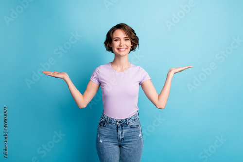 Photo of positive cheerful girl hold hand present ads promo object product offer wear good look outfit isolated over blue color background