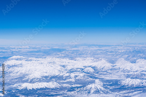 a landscape view from an airplane of snow-capped rocky mountains