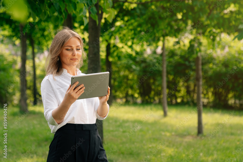 Portrait of confident business girl looking at the camera. Businesswoman holds digital tablet in hand, stern look Portrait of confident business girl looking at the camera. Businesswoman holds digital tablet in hand, stern look