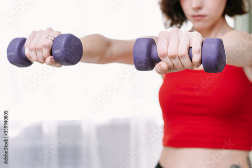 Lovely woman goes in for sports with dumbbells at home. Determined woman losing weight at home and exercising with dumbbells. Sport and recreation concept © etonastenka