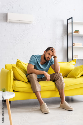 Selective focus of man suffering from heat on couch at home