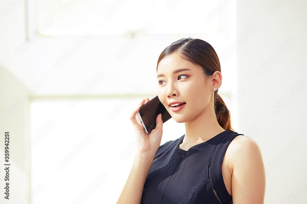 Young and beautiful Asian female business person is talking to someone on her smartphone. Young and beautiful Asian female business person is talking to someone on her smartphone.