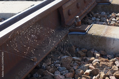 a large aerial web hangs on rusty metal  rails