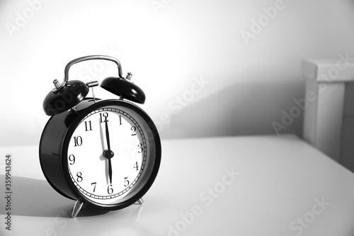 Wake up concept. Close up view of alarm-clock in morning bedroom environment. An image of a retro clock showing 06:00 am. 