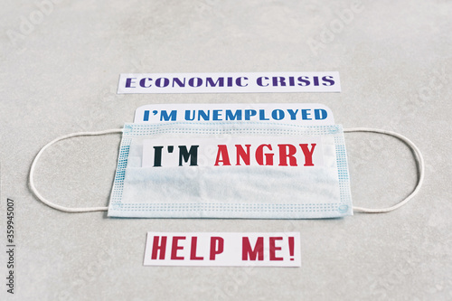 Blue medical mask on a light beige background. Medical background. Text "I am angry. Economic crisis. Help me. I am unemployed".