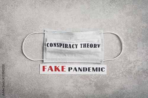 Fake pandemic. Conspiracy theory. The inscription on a light gray background and a medical mask. Fake news during corona virus / COVID-19 