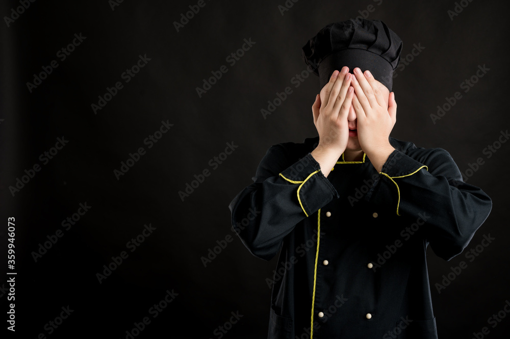 Young male dressed in a black chef suit covering eye like blind concept