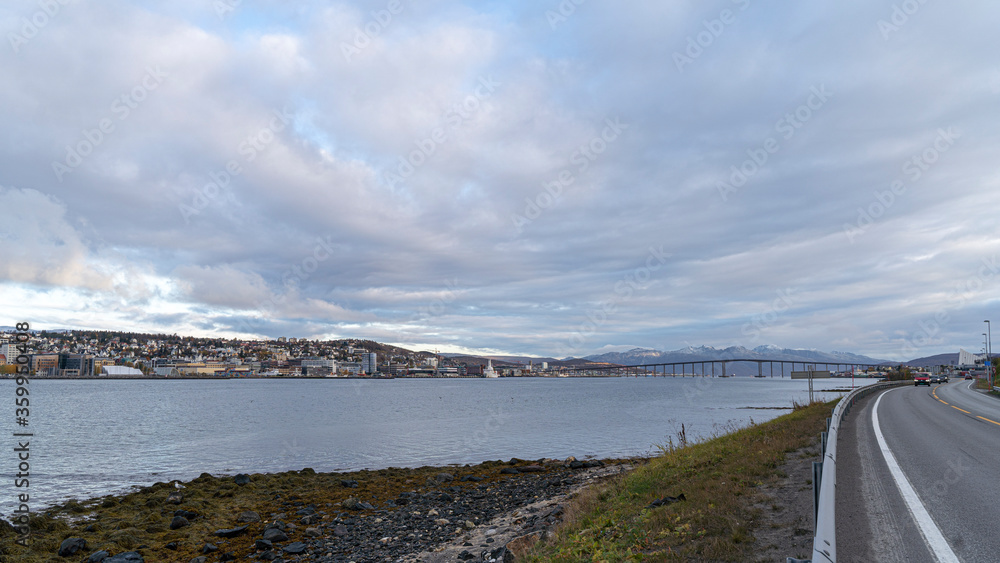 Blick entlang der Küstenstraße auf die Insel Tromsoya mit der Stadt Tromsö, Norwegen
