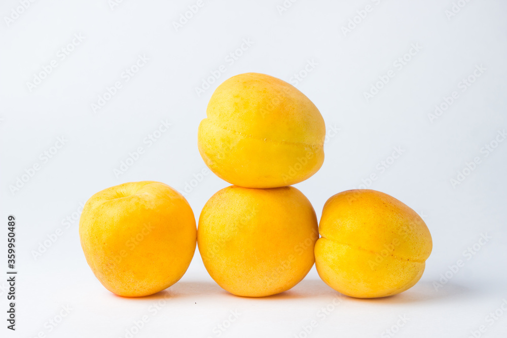 Apricots on a white background. One apricot lies on top of the others.